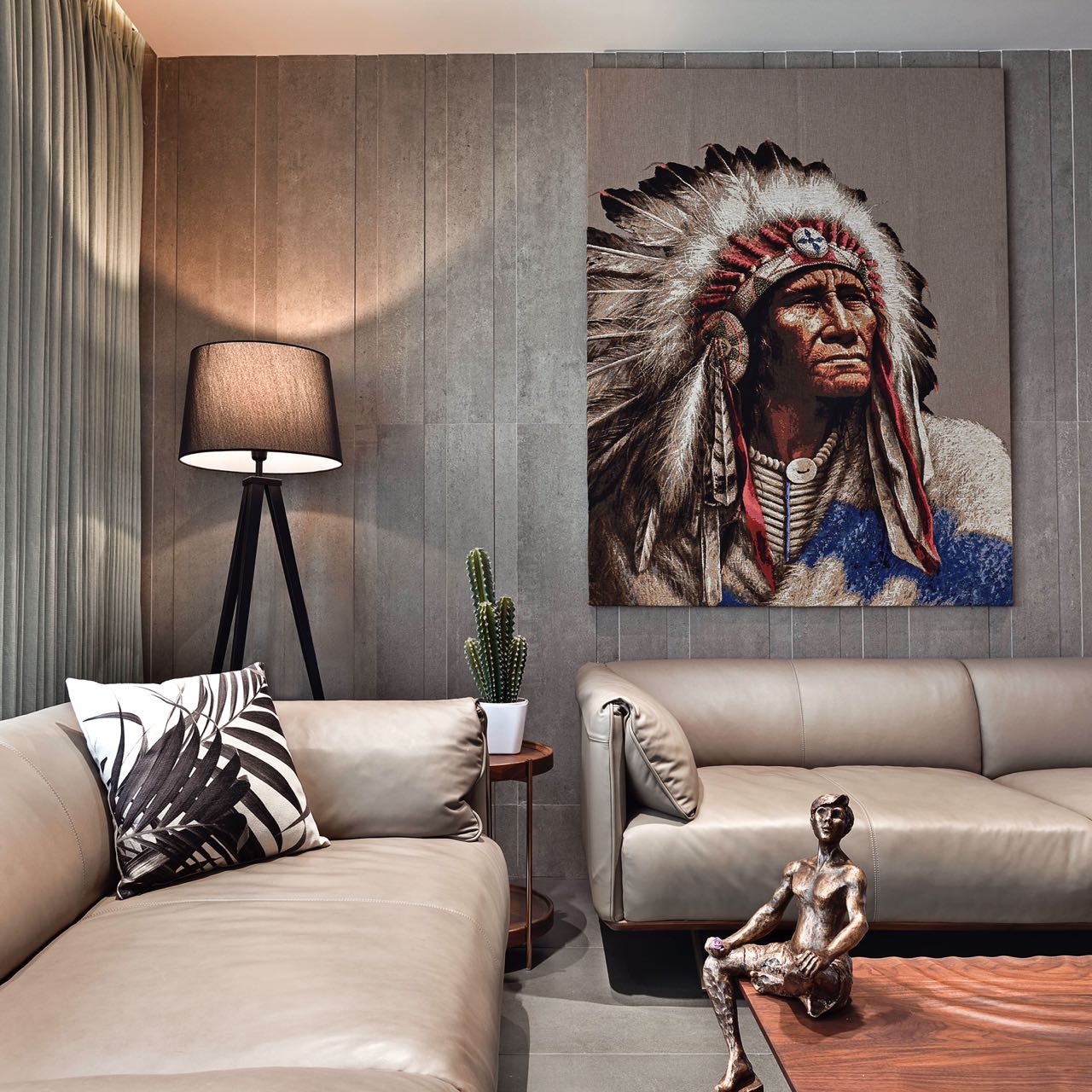 MA HOME leather sofas and tripod lamp below the large chief portrait on grey stone panelling
