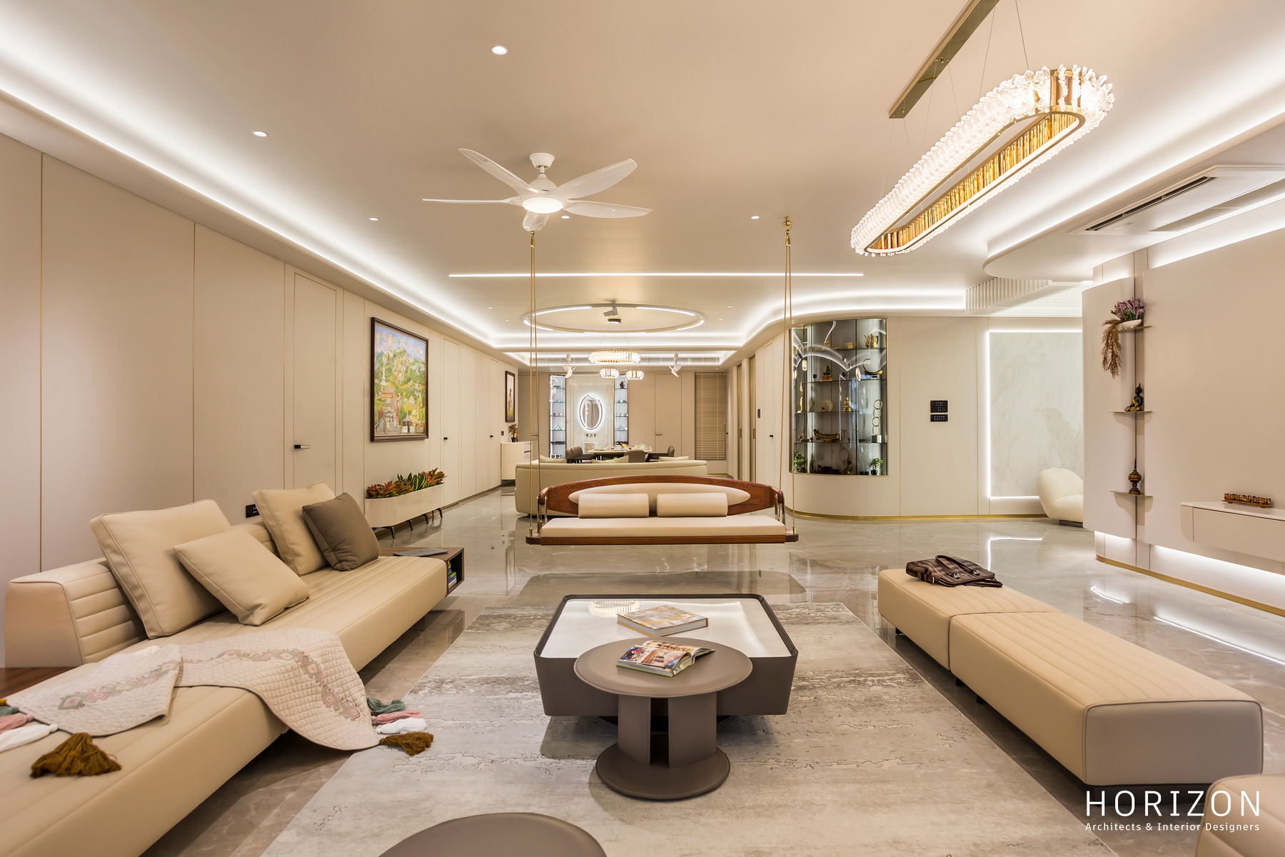 RAHUL BHAI HOME living room seen from the windows: long sofa, bench seat, round coffee table and lit display niches