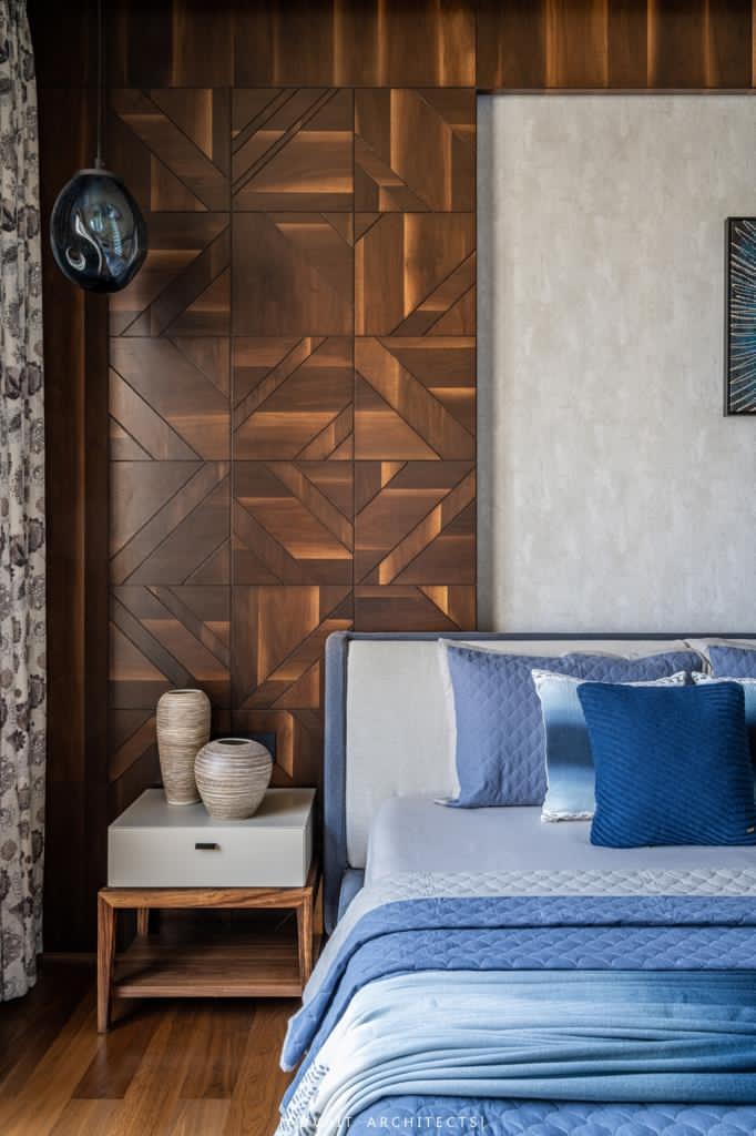 VILLASHBHAI HOME bedroom with a faceted timber panel wall and layered blue bedding