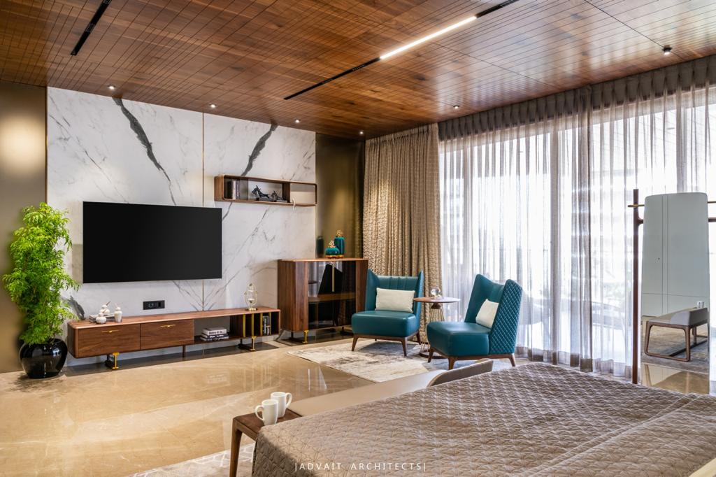 VILLASHBHAI HOME bedroom with marble wall, wall-mounted TV and a pair of teal chairs